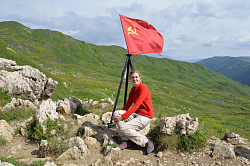 Девушка на фоне флага в горах, маршрут 30 через горы к морю