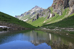 Это красивое горное озеро находится на туристическом маршруте Знаменитая Тридцатка - легендарный маршрут 30. Красивое горное озеро на фоне гор в снегу на турмаршруте в Краснодарском крае.